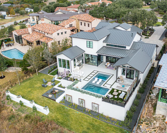 birds eye view of a large white modern home with a landscaped backyard